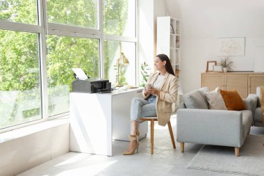 Ofisinde kahve ve matbaası olan genç bir iş kadını.