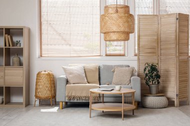 Katlanır perdeli şık bir oturma odası, rahat bir kanepe, sehpa ve raf ünitesi.