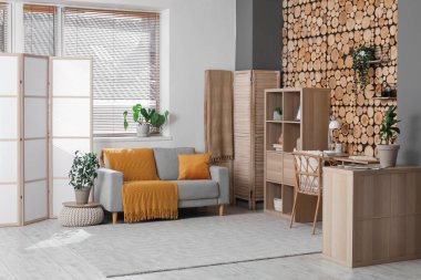 Katlanır ekran, rahat kanepe, iş yeri ve raf ünitesi olan şık bir oturma odası.