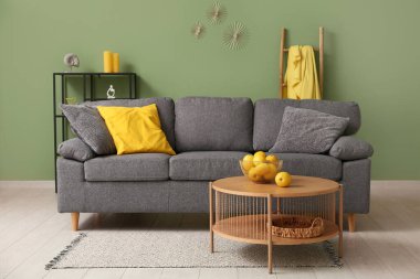 Modern oturma odasının içinde siyah kanepe, sehpa ve yastıkta portakallar.