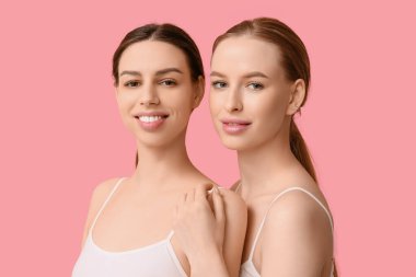 Pembe arka planda sağlıklı ciltli güzel, genç ve mutlu kadınlar.