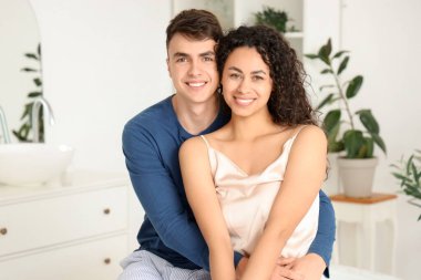 Genç çift banyoda sarılıyor.