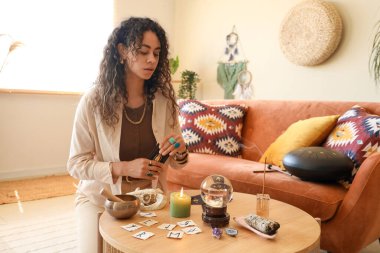 Genç Afro-Amerikalı cadı evde tarot kartları okuyor.