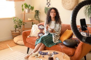 Genç Afro-Amerikalı cadı Tibet şarkı kasesi ile evinde video kaydediyor.