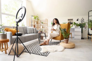 Koltukta kristal küreli genç Afro-Amerikan cadı evinde video kaydediyor.