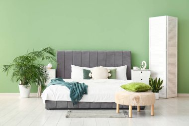 Sıcak yatak, komodin, katlanır ekran ve yatak odasında yastıkla puf.