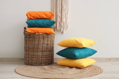 Renkli yastıklarla dolu Hasır sepet. Odadaki ışık duvarının yanında.