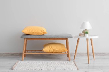 Sarı yastıklı yumuşak bank ve ışık duvarının yanındaki masa.