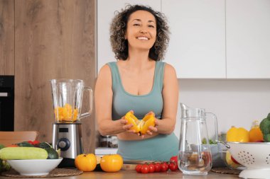 Dolmalık biber ve blenderlı olgun bir kadın mutfakta smoothie yapıyor.