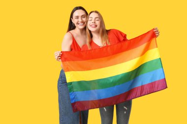 Sarı arka planda LGBT bayrağı olan güzel bir lezbiyen çift.