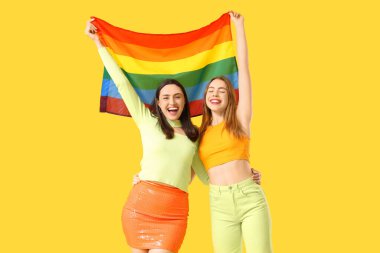 Sarı arka planda LGBT bayrağı olan güzel bir lezbiyen çift.