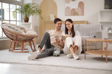 Evde defterine para dolu bir kavanoz yazan genç çift.