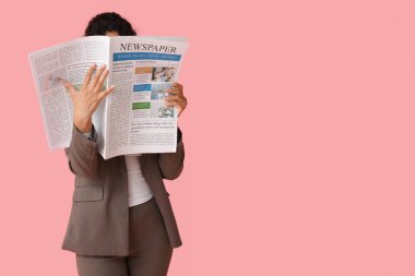 Pembe arka planda gazetesi olan genç bir Afro-Amerikalı kadın.