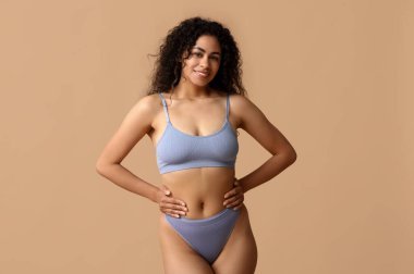 Güzel, genç, mutlu, Afro-Amerikan kadın bej arka planda şık iç çamaşırlı.