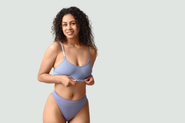 Gri arka planda şık iç çamaşırlı güzel, mutlu, Afro-Amerikan kadın.