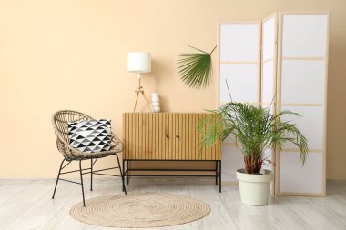 Katlanan ekran, klozet ve bej duvarın yanındaki sandalye olan odanın içi