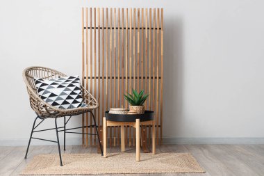 Beyaz duvarın yanında ahşap perde, sandalye ve sehpa olan bir oda.