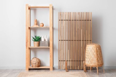 Odanın içi ahşap perdeli, hasır lambalı ve beyaz duvarın yanındaki raf üniteli.