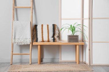 Beyaz duvarın yanında katlanır ekran, merdiven ve bank olan odanın içi