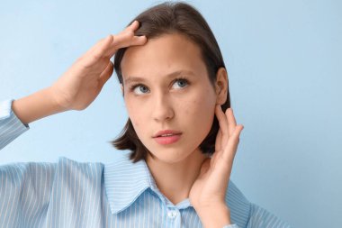 Mavi arka planda sivilce sorunu olan güzel bir genç kadın.