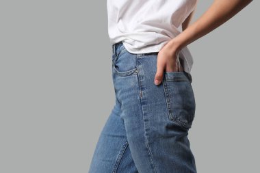 Gri arka planda şık kotlu güzel genç bayan, yakın plan.