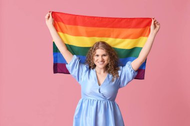 Pembe arka planda LGBT bayrağı olan güzel genç bir kadın.