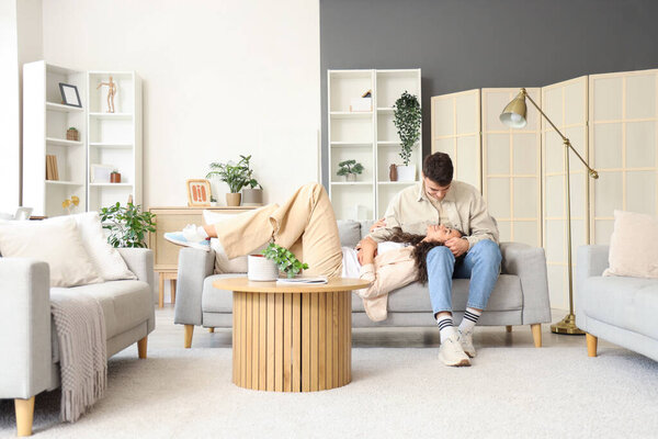 Молодая пара влюбленных отдыхает дома на диване