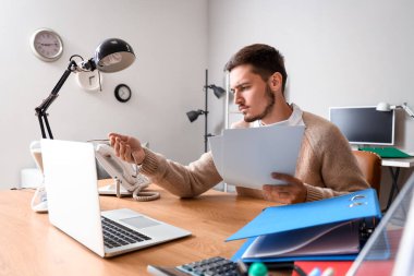 Genç adam ofiste kol saatine bakıyor. Son teslim tarihi kavramı