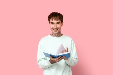 Pembe arka planı olan dövmeli genç bir adam.