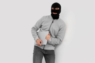 Dizüstü bilgisayarlı bir erkek hırsız merdivenlerden kaçıyor.