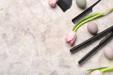 Kuaför fırçaları, laleler ve hafif grunge arka planda Paskalya yumurtalarıyla düzleştirici demir.