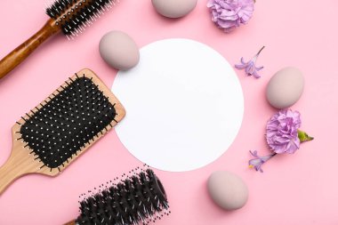 Saç fırçaları, çiçekler ve pembe arka planda Paskalya yumurtaları olan boş bir kart.