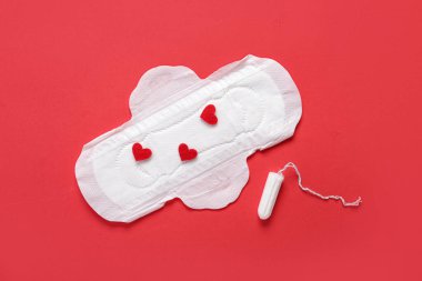 Kırmızı arka planda kalp ve tampon olan adet yastığı.