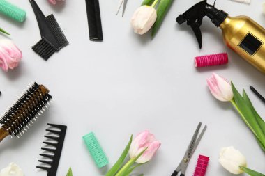 Gri arka planda güzel laleleri olan kuaför aletlerinden yapılmış çerçeve