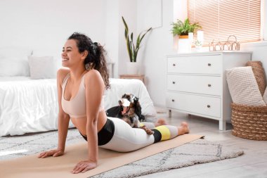 Cocker Spaniel 'le birlikte yatak odasında yoga yapan Afro-Amerikan bir kadın.