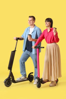 Kahve fincanlarına aşık genç bir çift ve sarı arka planda scooterlar.
