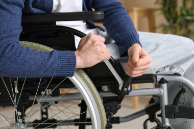 İngiliz anahtarı olan genç adam tekerlekli sandalyesini tamir ediyor, yakın plan.