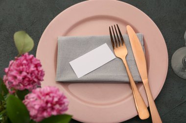 Boş davetiye kartı ve siyah arkaplanda çiçekler olan güzel masa ayarları