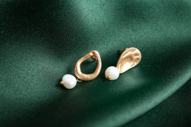 Yeşil kumaş arka planda güzel küpeler.