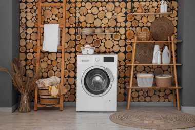 Çamaşır makinesi, sepeti ve raf ünitesi olan çamaşır odasının içi.