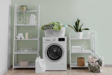 Interior of laundry room with washing machine, baskets and shelf units