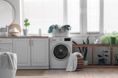 Çamaşır sepetinin çamaşır makinesinde olduğu banyo.