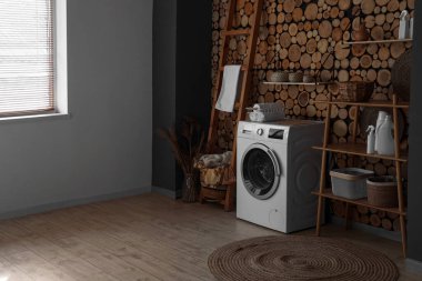 Çamaşır makinesi, sepeti ve raf ünitesi olan çamaşır odasının içi.