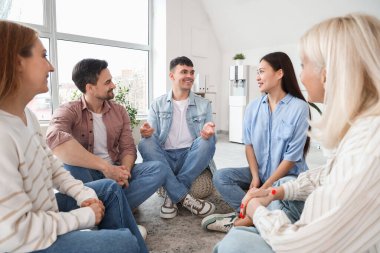 Grup terapisinde gülümseyen genç adam konuşuyor.