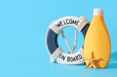 Bir şişe güneş kremi, dekoratif can simidi ve arka planda deniz yıldızı.