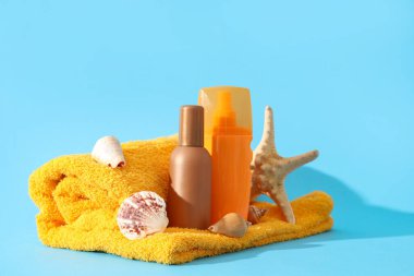 Renkli arkaplanda güneş kremi, havlu ve deniz dekoru şişeleri