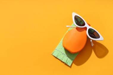 Renkli arkaplanda güneş kremi ve güneş gözlüğü olan kompozisyon