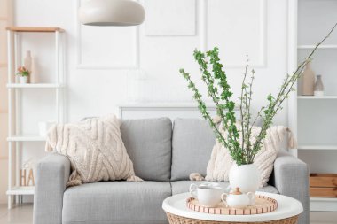 Rahat bir kanepe, sehpa ve vazo, güzel oturma odasında çiçek açan dallar.