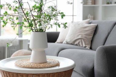 Oturma odasındaki masanın üzerinde çiçek açan bir vazo.