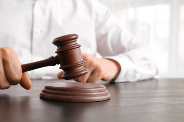 Hakim tokmağı olan erkek avukat masada oturuyor, yakın plan.